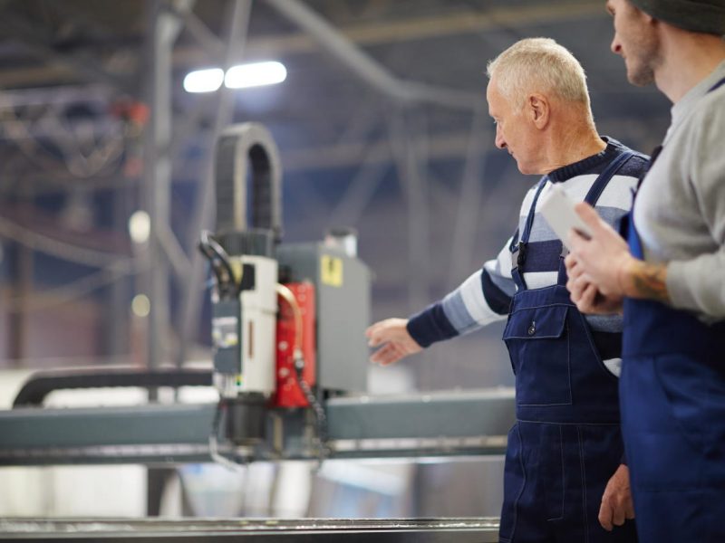 Two professionals in workwear discussing engine system of new boat during work in factory
