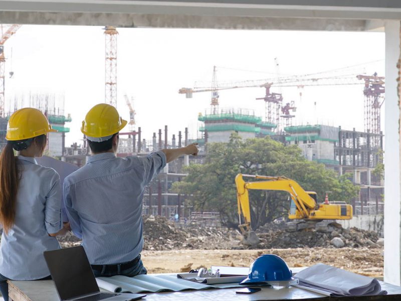 Engineer group and worker meeting, discussion with construction blueprint on site work and point finger to the work site