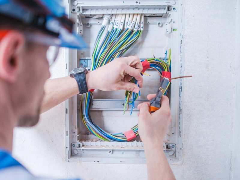 Caucasian Electric Technician in His 30s Installing Electrical System Inside Newly Remodeled Apartment.